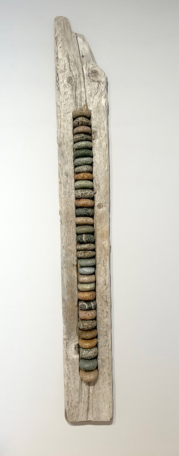Decorative wall art with stacked stones on a wooden base against a white background