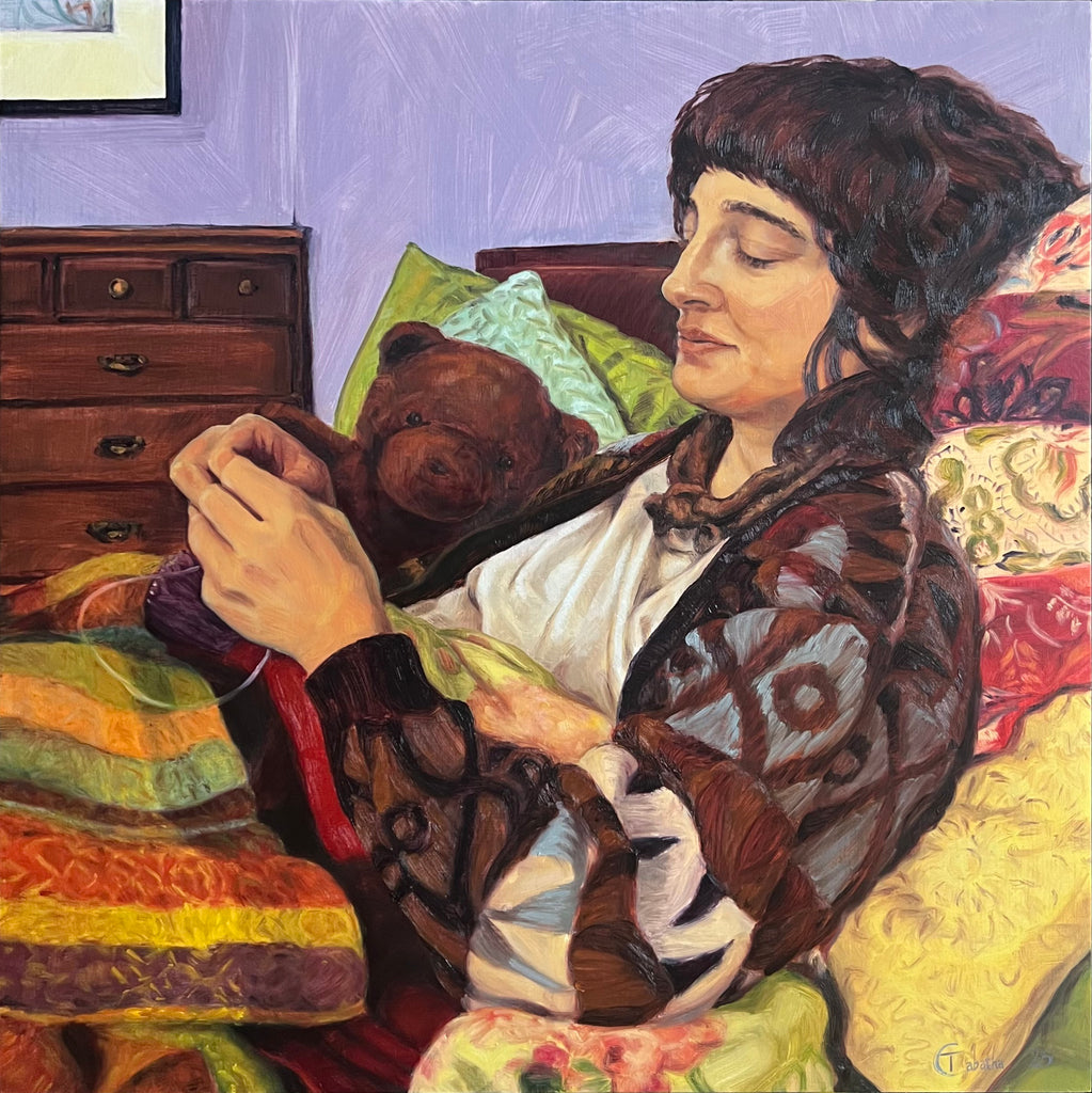 Woman holding a teddy bear in a bedroom setting with colorful bedding and furniture.