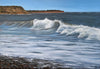 A landscape painting of ocean waves rolling onto a rocky shore under a clear blue sky, with a brown cliff in the background.