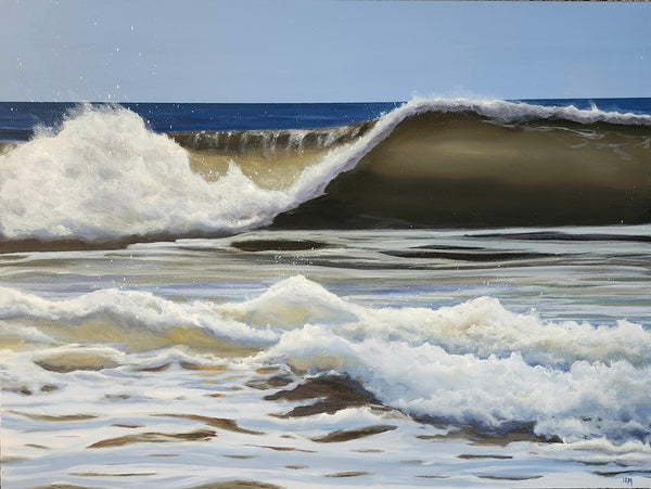 Wave crashing onto a beach with a clear blue sky