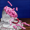 Still life painting of pink candy sticks spilling out of a silver teacup on a blue background.