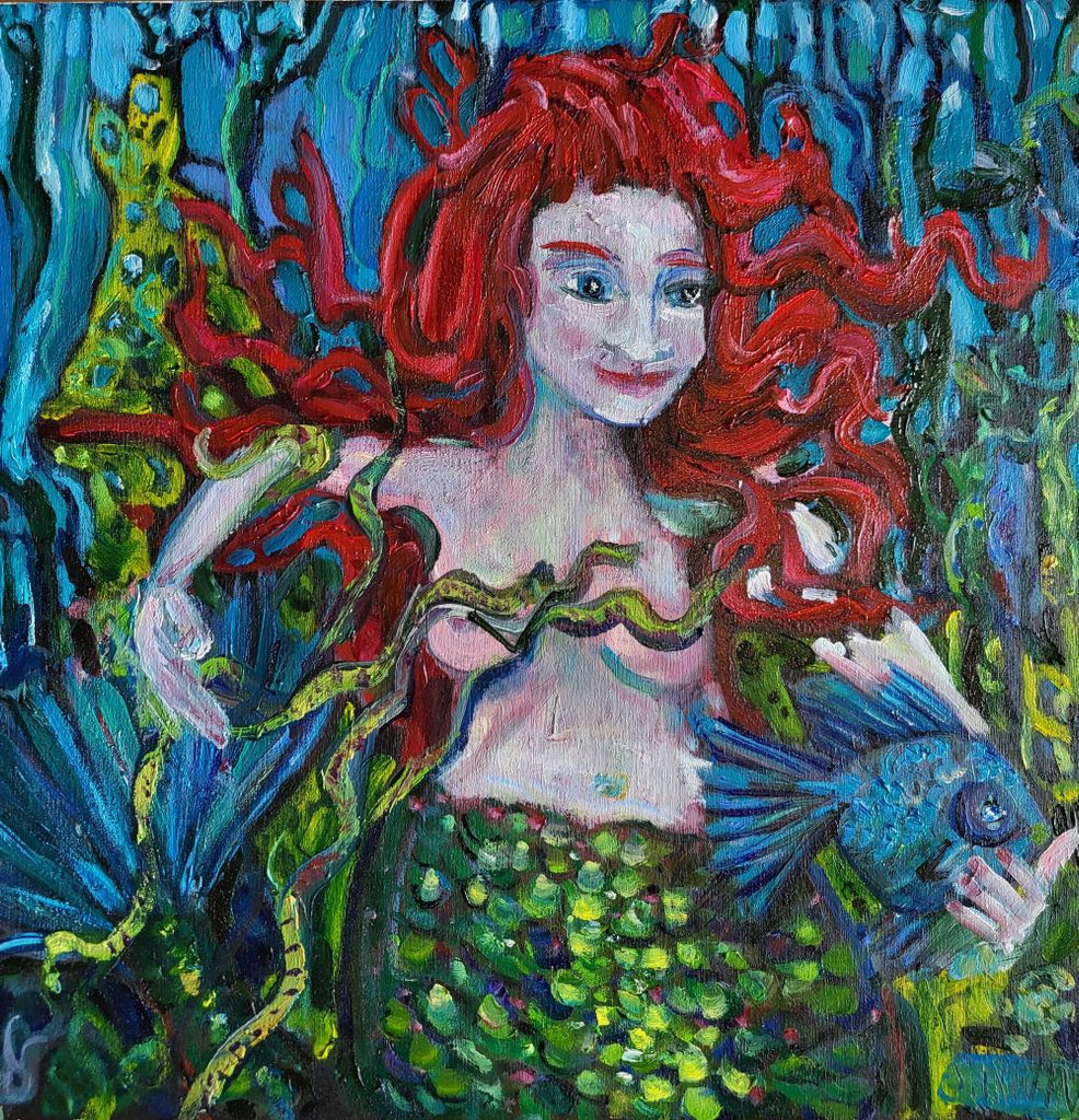 a red headed mermaid cradles a blue fish