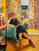 Woman sitting in a chair reading a book in a colorful room.