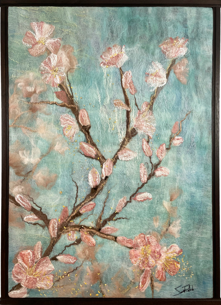 In this felted textile work, a branch studded with pink apple blossoms rises from the left corner. Sanna Rahola uses silk, mohair, and wool to capture this image. 
